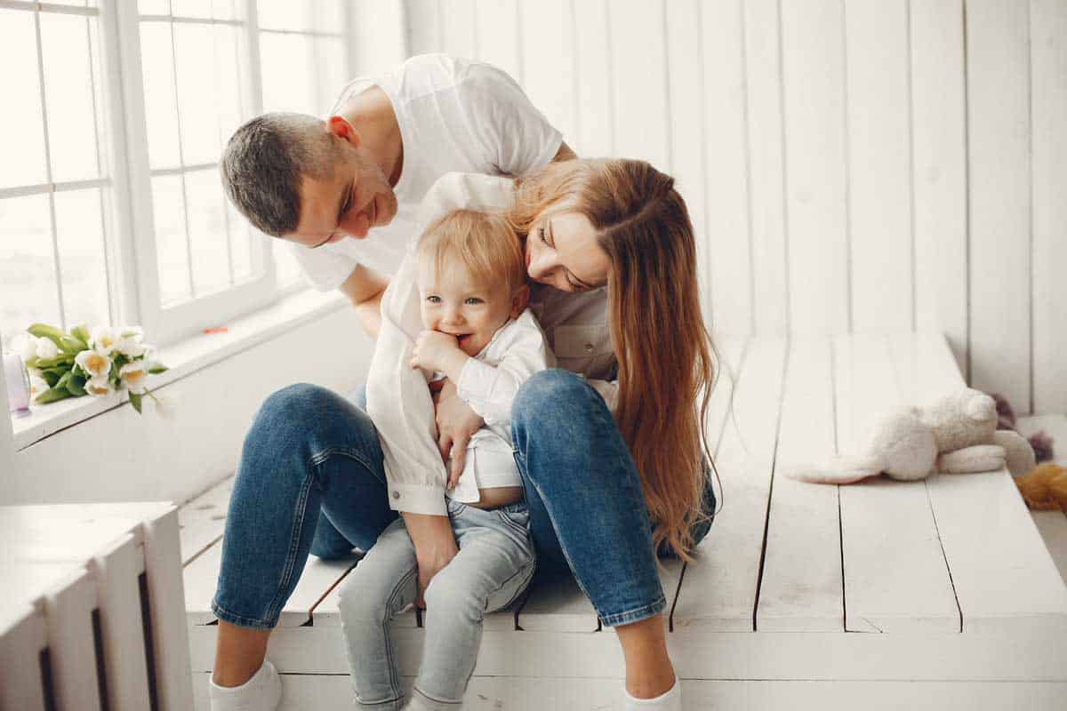 Family together where Father and mother hugging their baby on white rustic wooden room