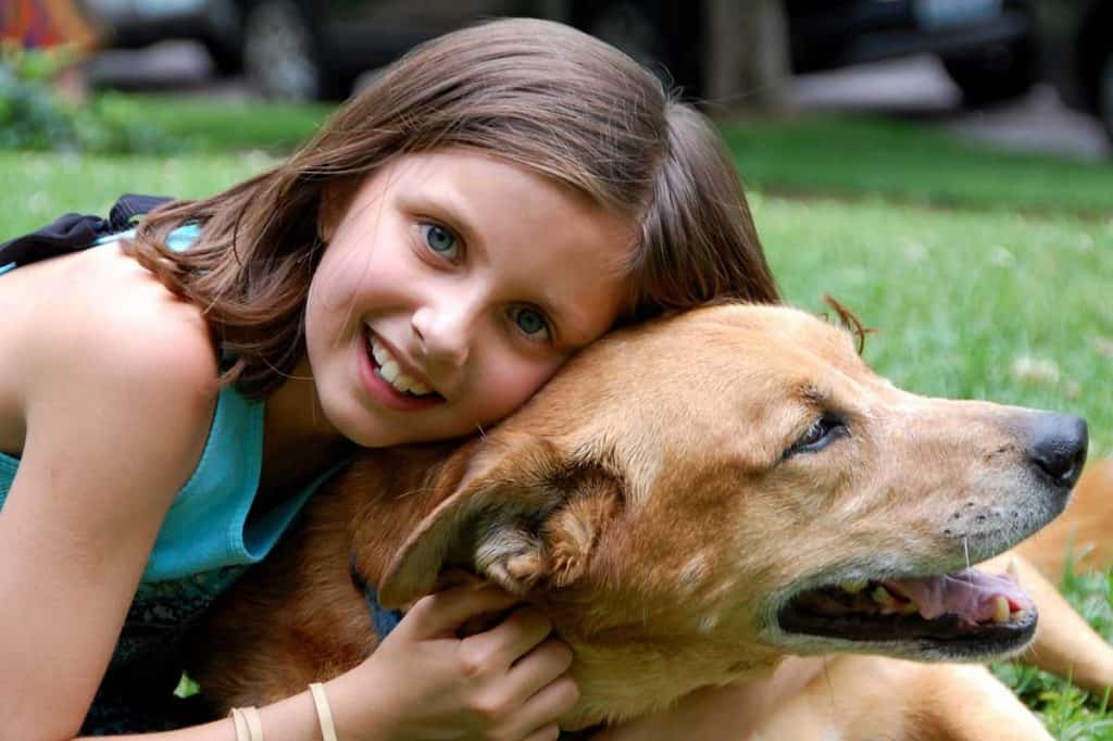 A girl hugging her dog outdoors