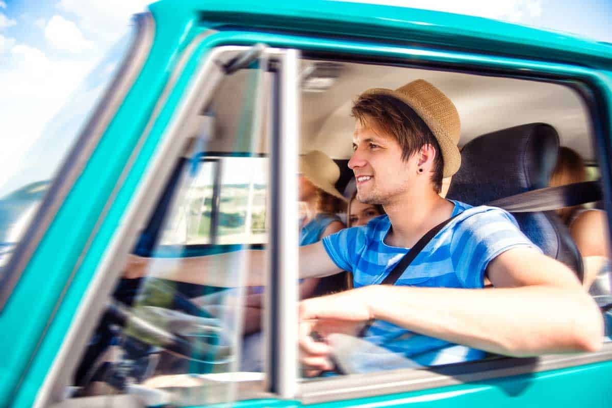 Man driving on a car with friends for roadtrip