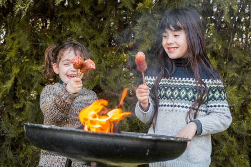 barbecue front two happy girls holding sausages