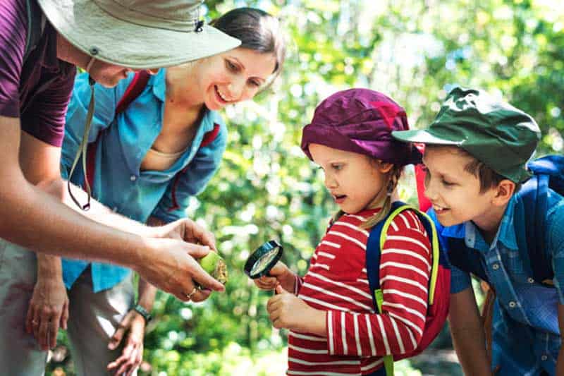 father teaching his daughter how use magnifying glass