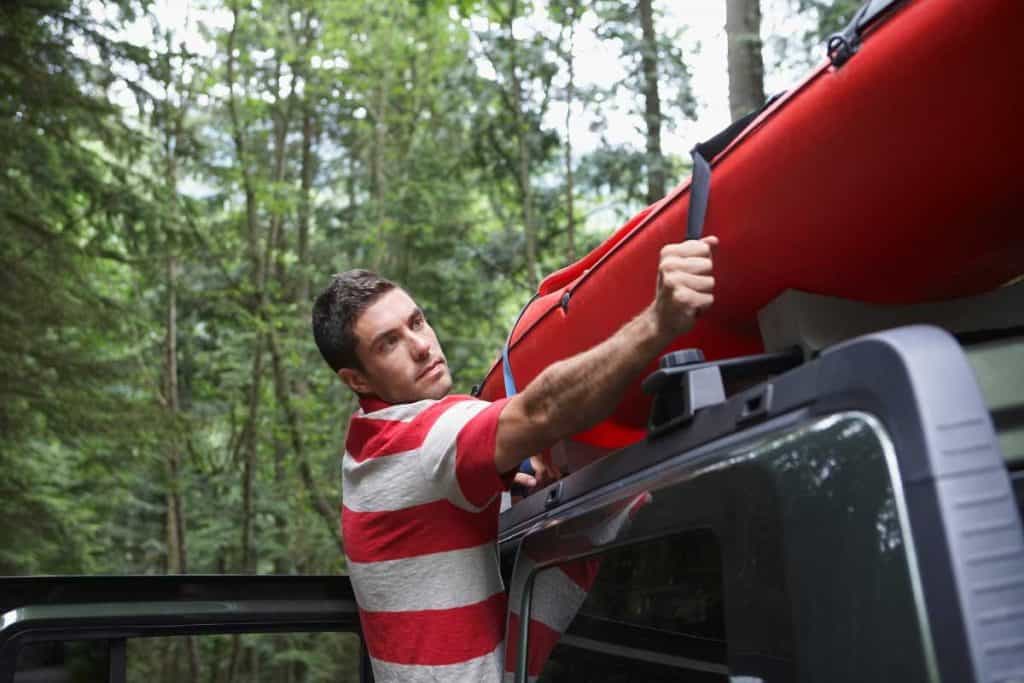 Man securing his canoe on the car rack