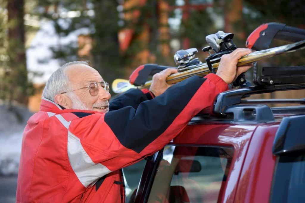 Old man securing luggage on car rack